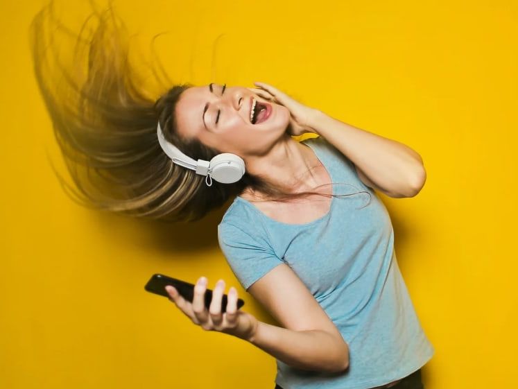 Woman With Headphones On Listening To A Music Device And Singing Flicking Her Hair